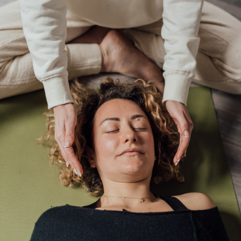 Reiki meditation with woman laying down and other hands next to her head